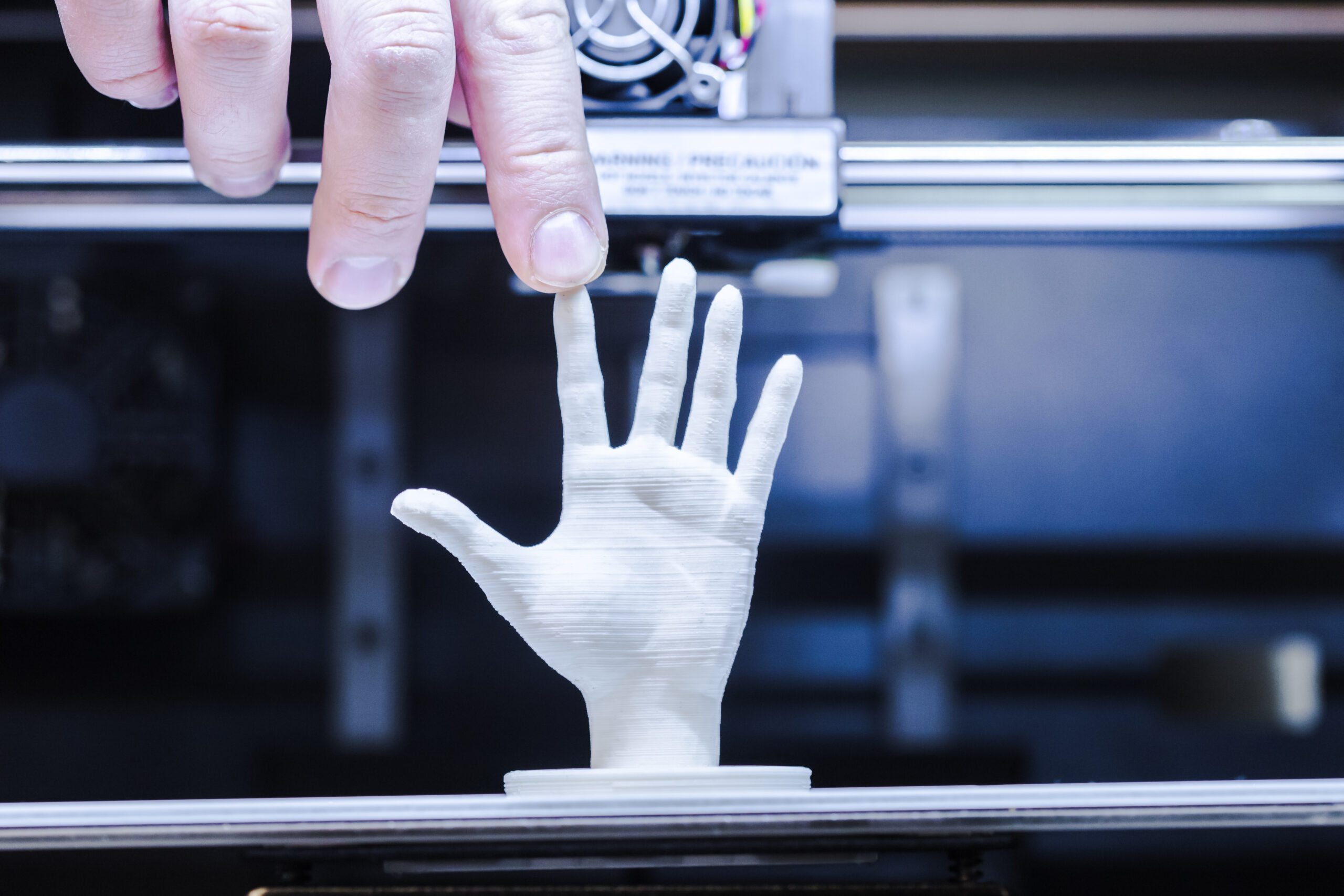 A man is doing 3d Printing with help of white masterbatch used in hand sculpture